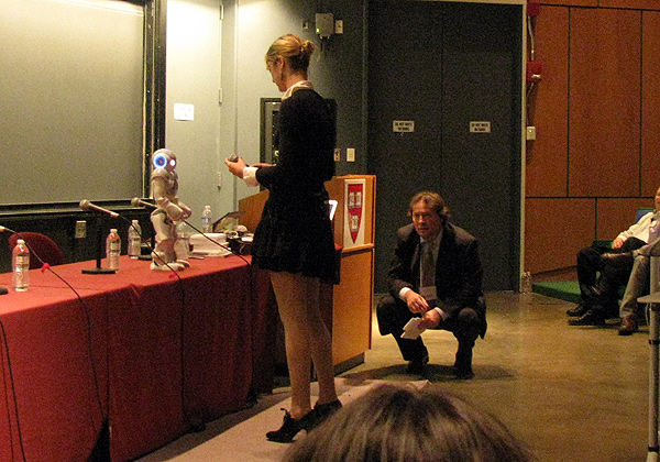 Fem and bot: Heather Knight faces her 'Star Wars'-performing robot, while H+ chairman David Orban looks on, kneeling.